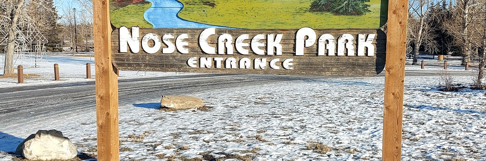 Nose Creek Park entrance sign in Airdrie, Alberta, with snow on the ground