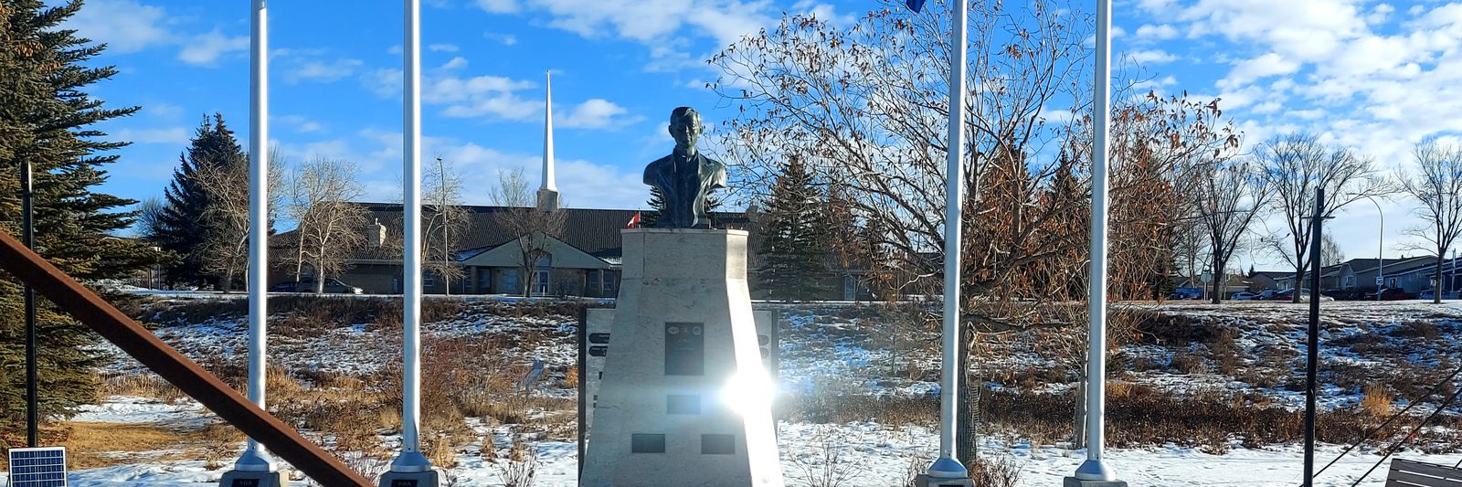 Jose Rizal monument and flagpoles at Nose Creek Park in Airdrie, Alberta, on a sunny winter day